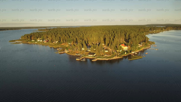 Aerial view of Piteå archipelago: Forested island with coastal houses and docks in Swedish waters