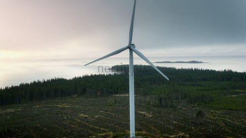 Roterande vindturbin: Generering av ren energi mot kustsolnedgång och molnig himmel