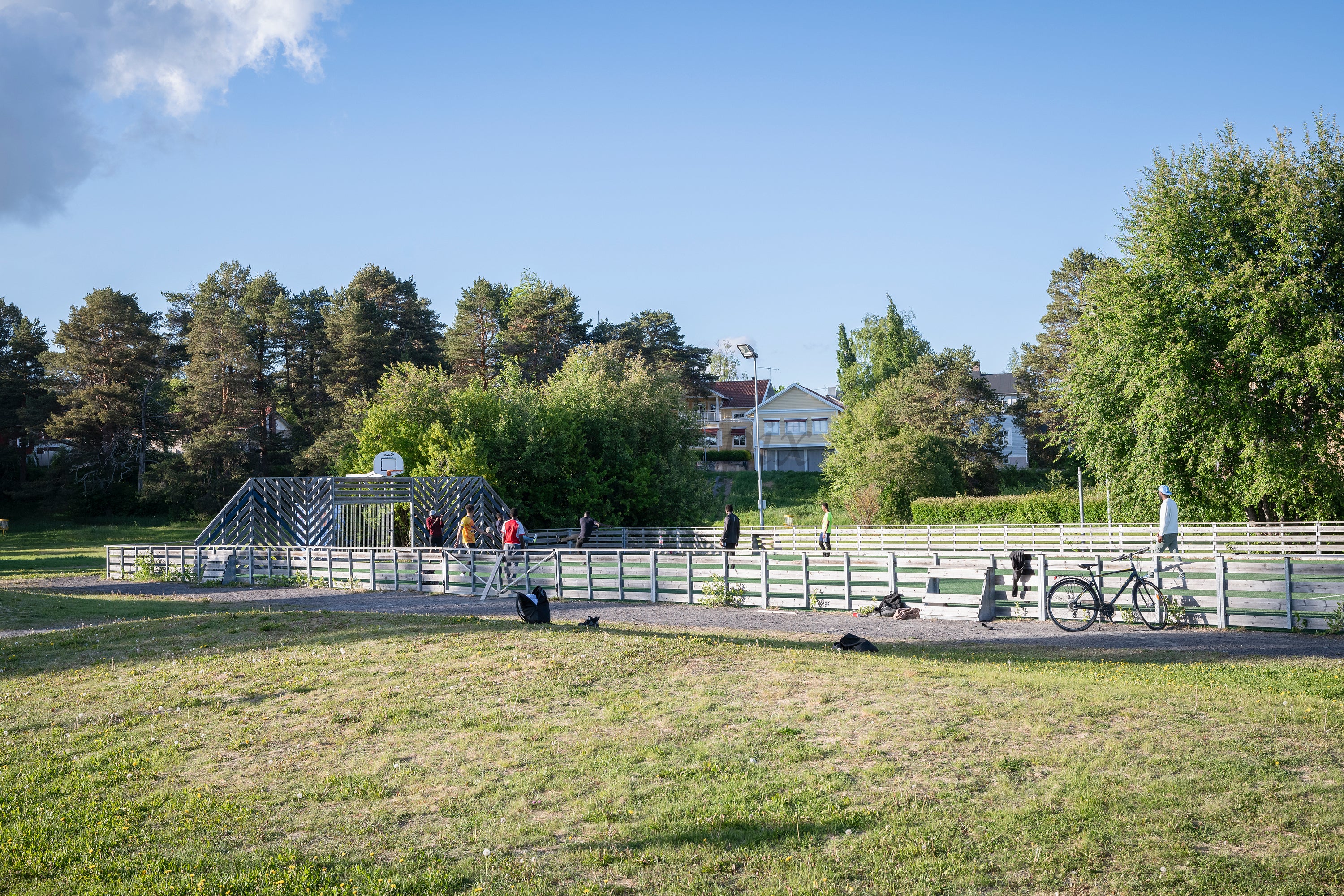People on fenced outdoor court in summer afternoon