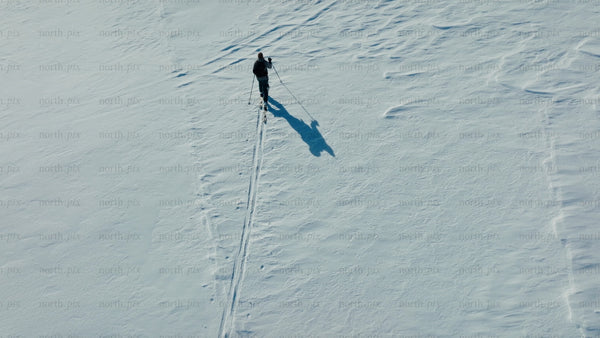 Skier crosses snowy mountain on sunny winter day