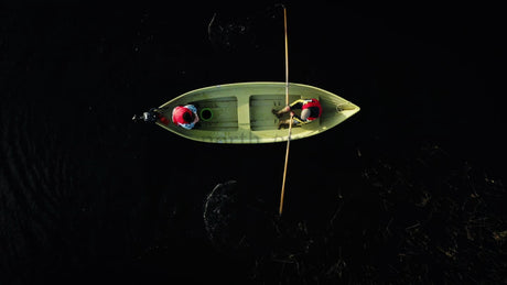 Summer Crayfish Fishing: Two People Rowing a Small Boat on a Dark Lake in Luleå, Sweden