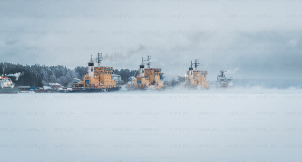 Icebreaker ships lined up along frozen harbor