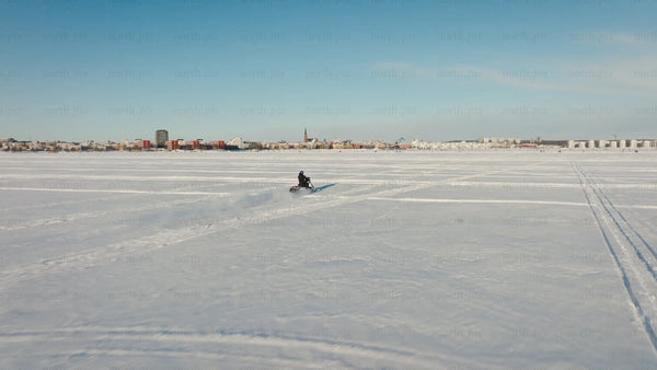 Snowmobile riding across frozen lake in Luleå - winter landscape