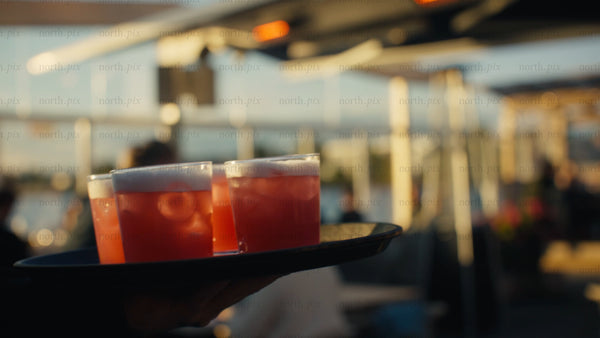 Waiter carries cocktails at sunset restaurant in Luleå urban summer