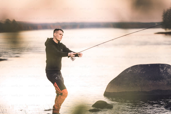 Man fly fishing on a lake shore at dusk
