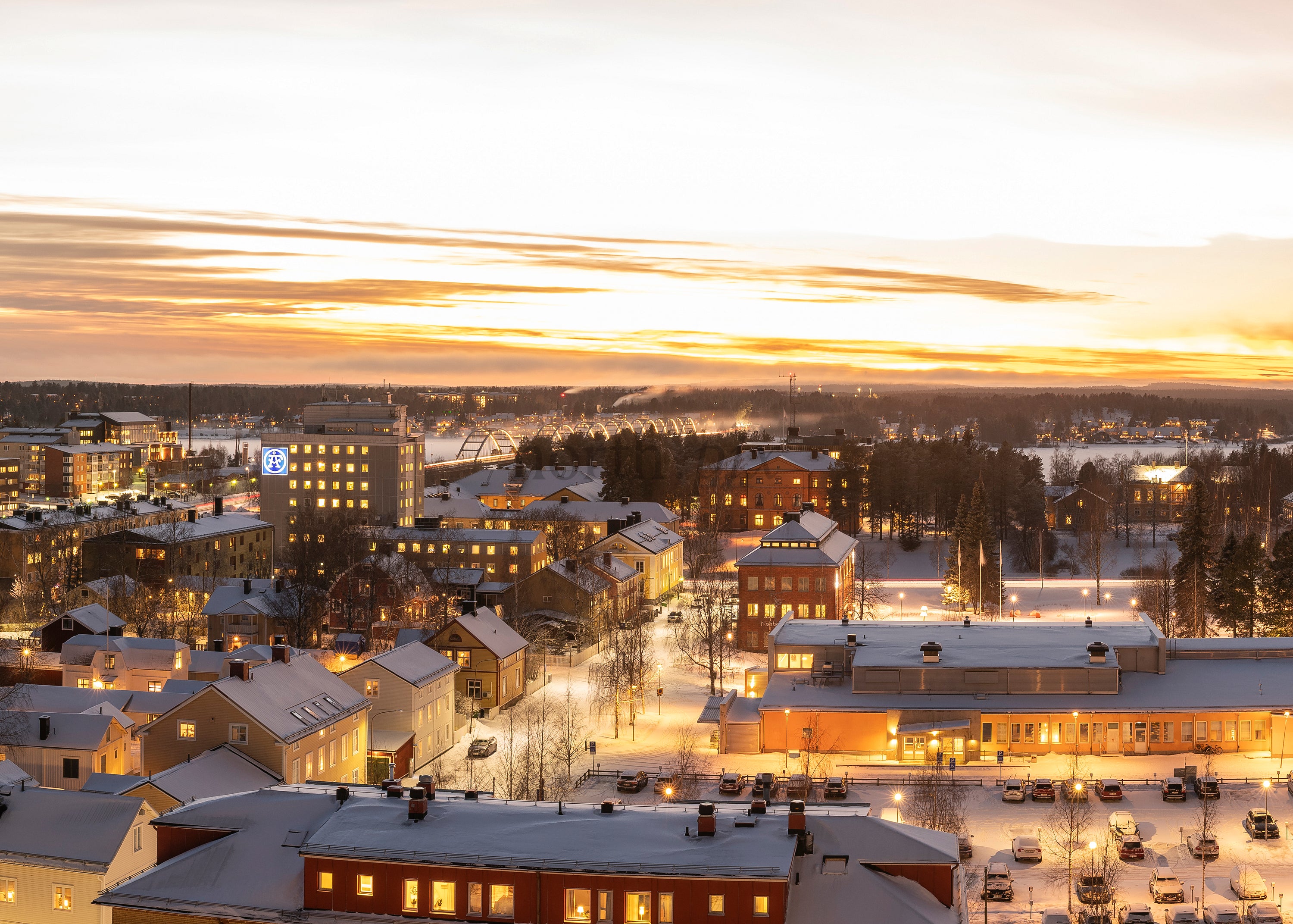 Snow-covered Luleå at sunrise with lit buildings