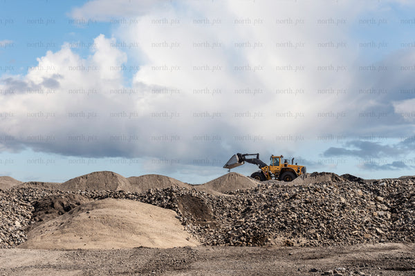 Wheel loader moving gravel on construction site during day