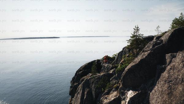 Drone view of rocky cliff and boat in Luleå archipelago, on bright summer day