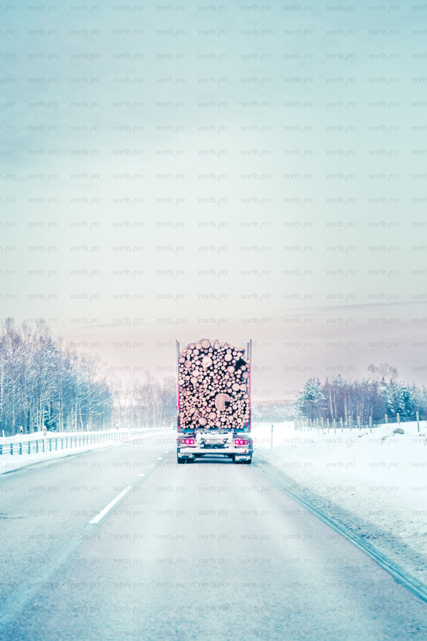 Log truck on snowy highway in winter morning