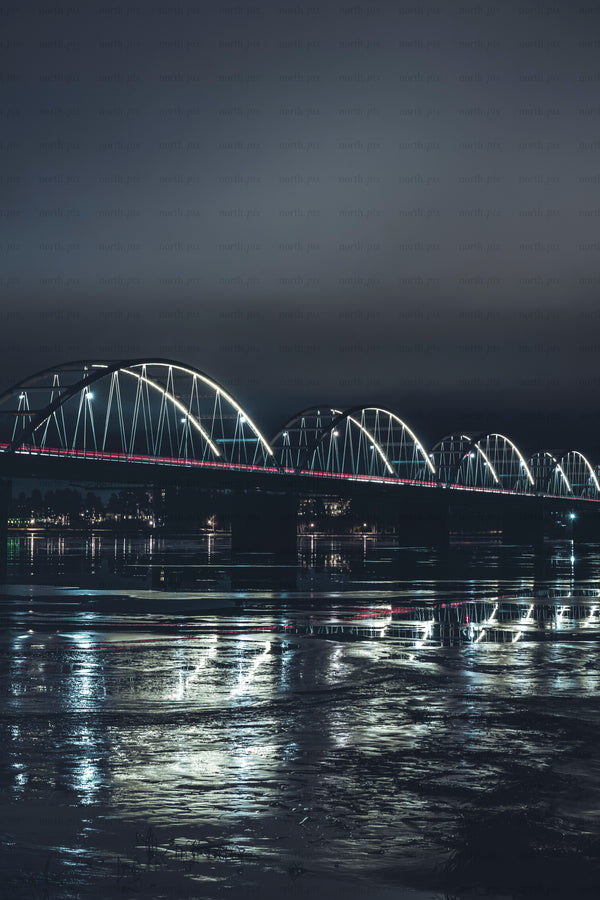 Illuminated arched bridge over river at night