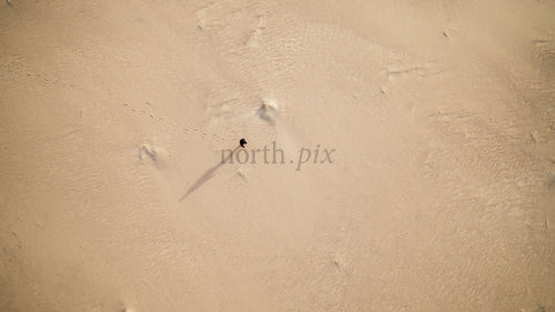 Flygfoto över person som går på sandstrand i Skvalpens skärgård, Luleå, Sverige