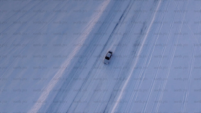 White car on a snowy ice road in Luleå during winter twilight