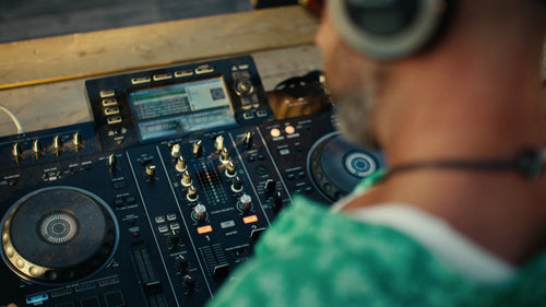 DJ mixar musik på controller utomhus vid solnedgången i Luleå