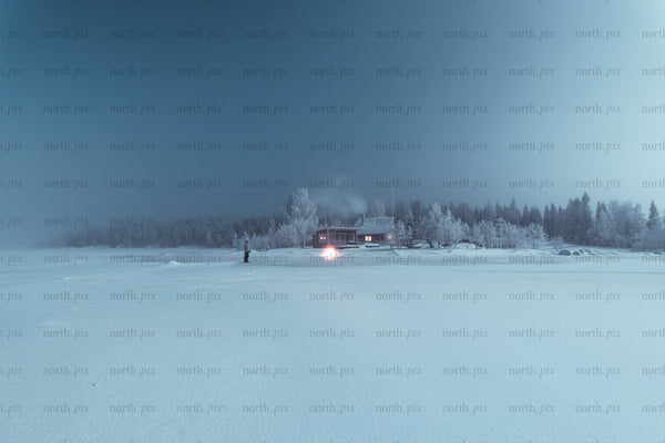 Cabin on a frozen lake at night in winter