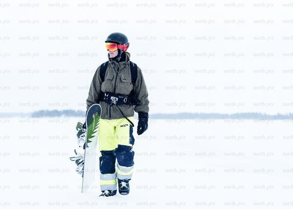 Snowboarder walking across snowfield in winter daylight