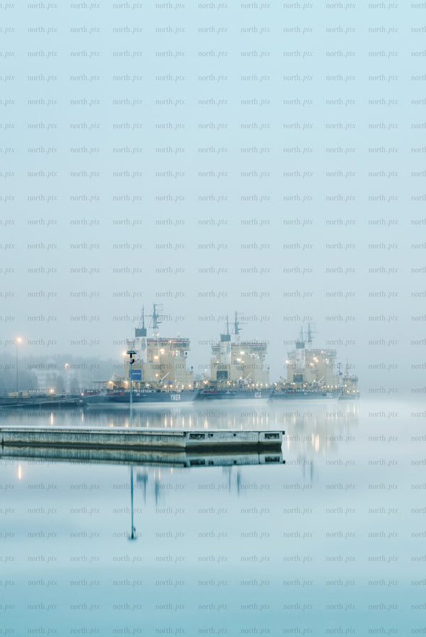 Three icebreakers docked at harbor in fog