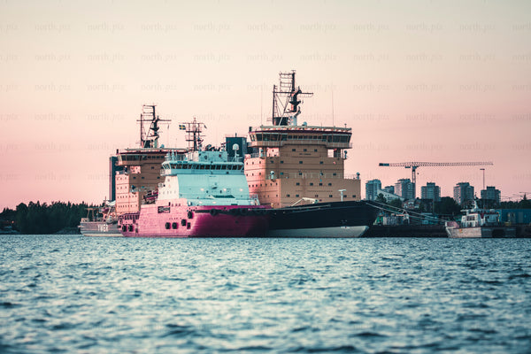 Ships docked at harbor at sunset