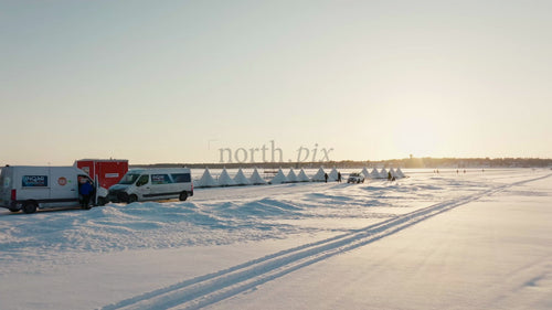 Drönarbild av snötäckta Luleå i vintersolnedgången, Sverige med tält och människor på fruset vatten