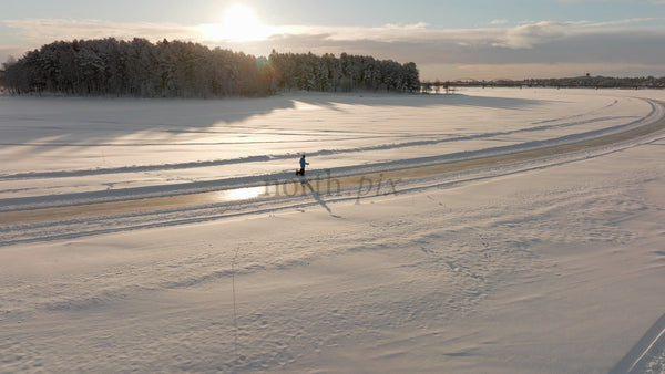 Winter Walk in Luleå: Person and Dog Enjoying a Scenic Sunset Over a Frozen River