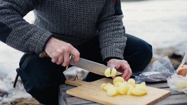 Man chopping potatoes outdoors in winter near Luleå