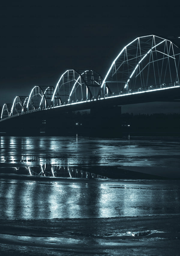 Illuminated arch bridge at night over river with reflections
