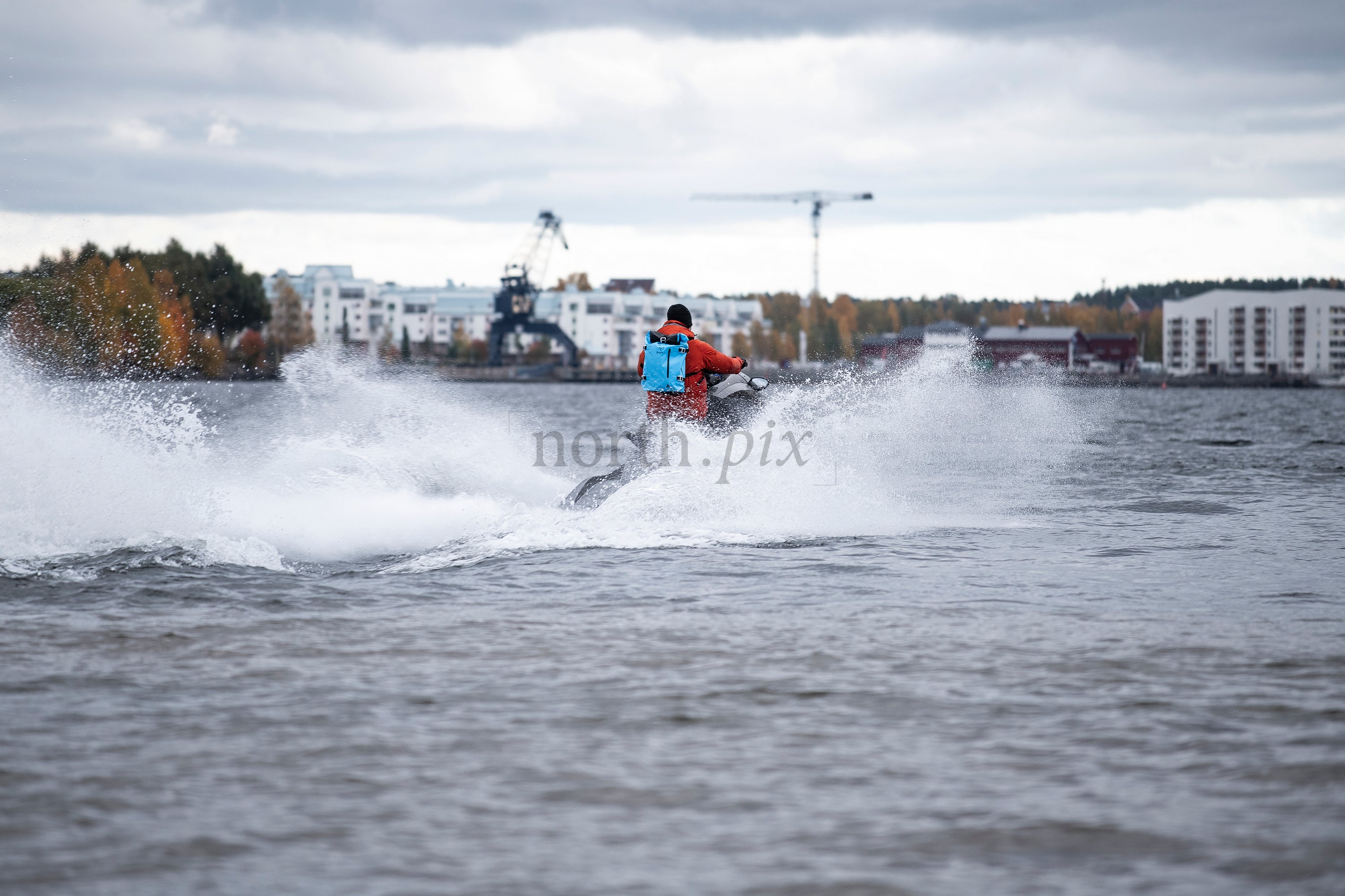 Person riding jet ski near harbor in autumn