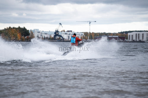 Person riding jet ski near harbor in autumn