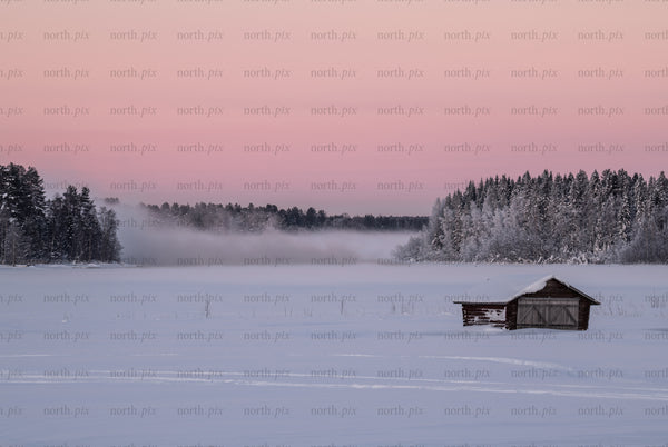 Boathouse on a frozen lake at sunrise