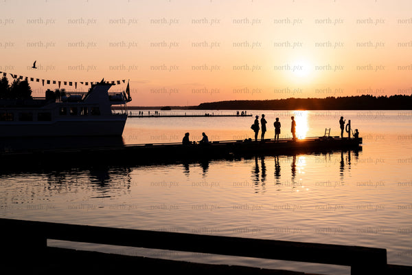 Silhouettes on pier at sunset over lake