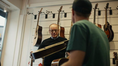 Guitar Shop Employee Assists Customer Choosing an Acoustic Guitar