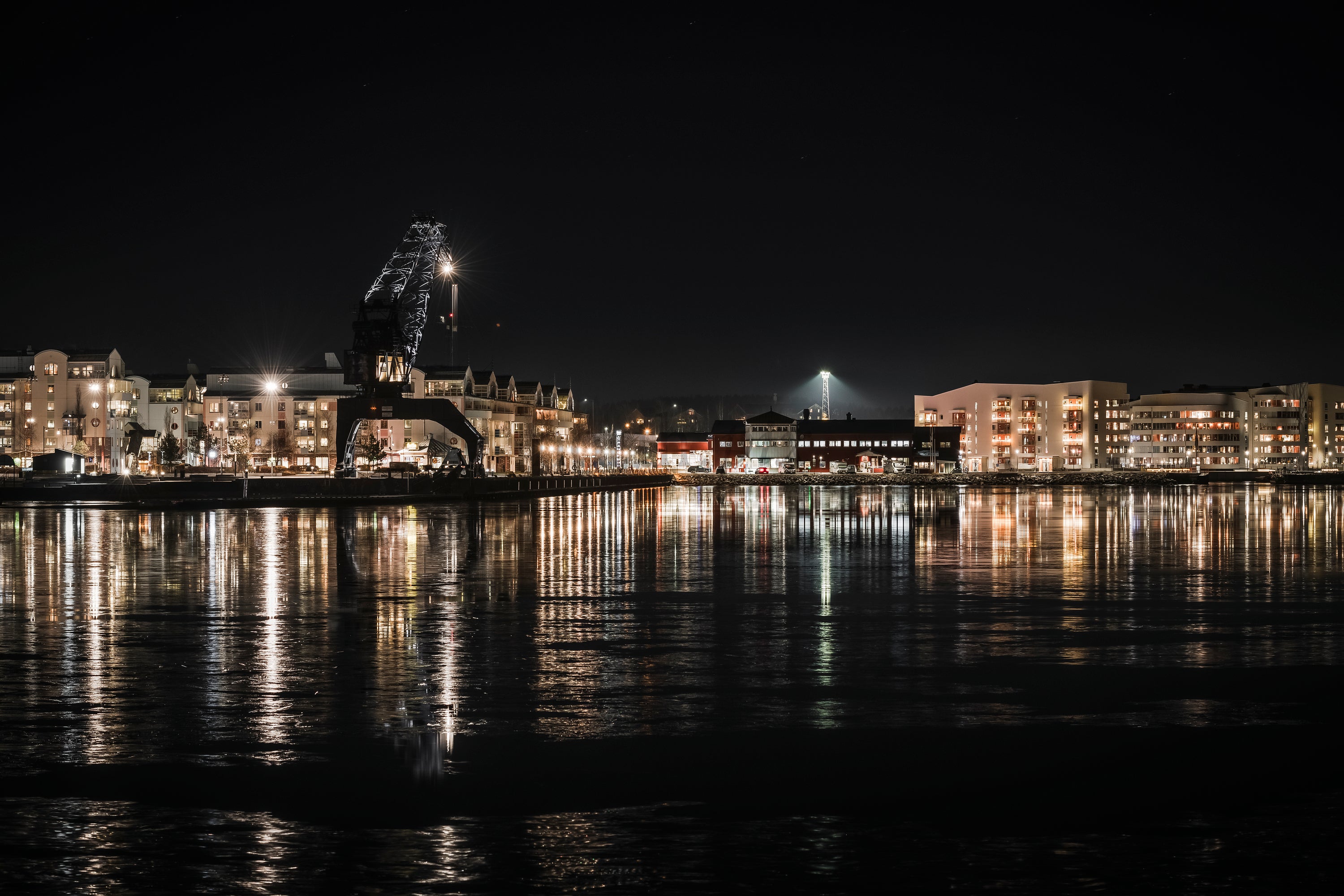 Luleå South harbor waterfront with crane and reflected building lights
