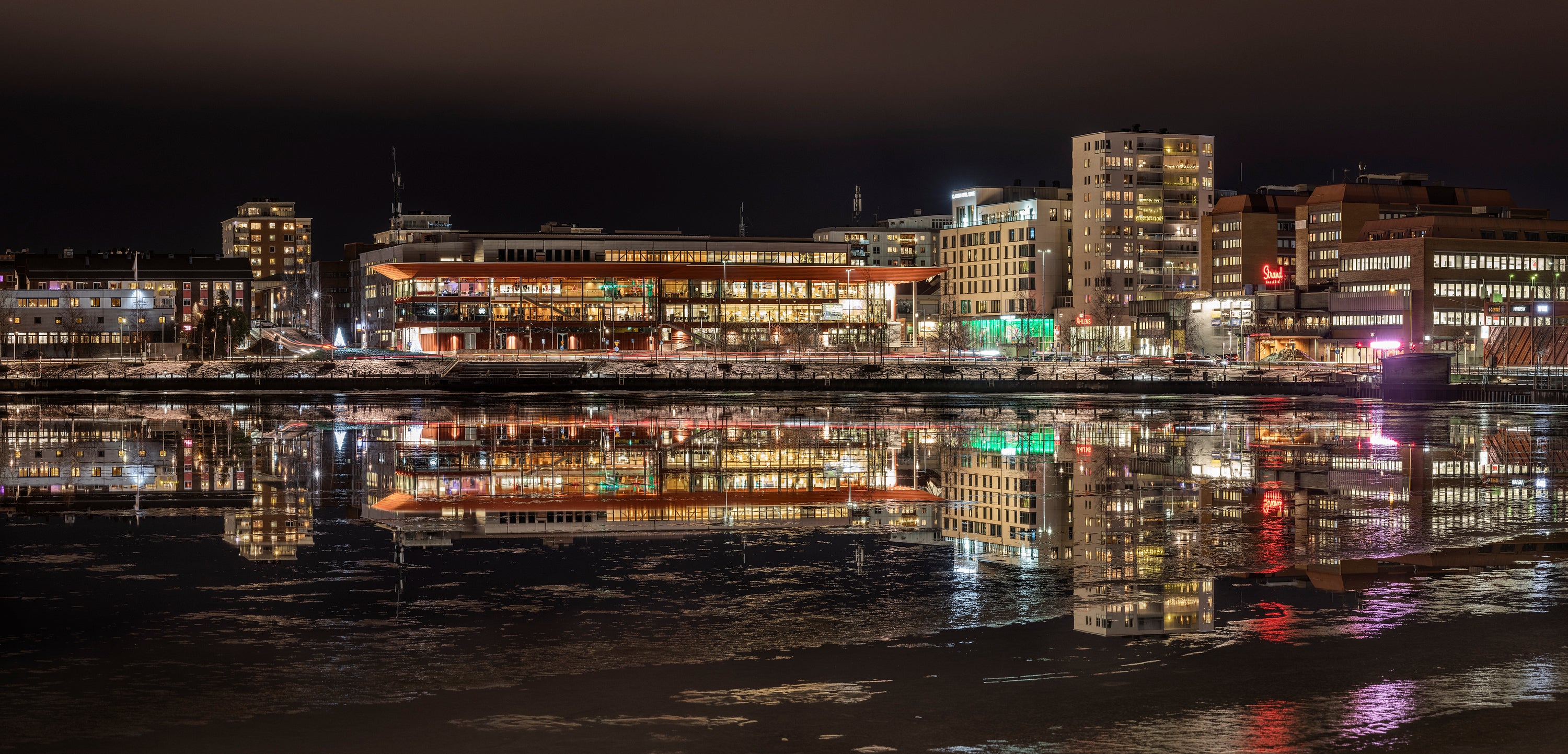 Riverfront buildings reflected on icy water at night