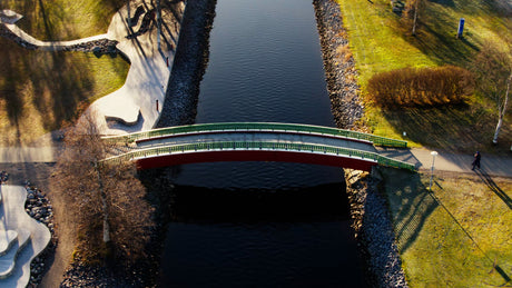Autumn Aerial View: Person Walking Across a Picturesque Bridge Over Piteå City Canal