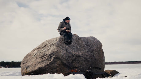 Man Enjoys a Warm Drink by a Fire on a Frozen Lake in the Luleå Archipelago, Sweden