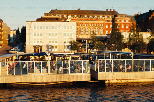 Outdoor riverfront dining at Luleå city center with glass-walled terrace over water