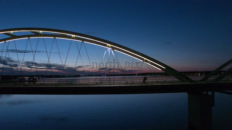 Cyclist Crossing Illuminated Bridge in Luleå, Sweden at Twilight