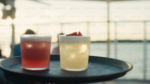 Waiter carries cocktails on a tray at an urban rooftop party during a summer evening