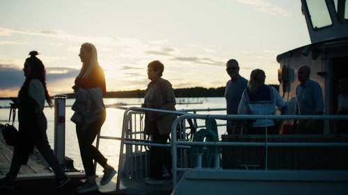 Vänner och familj går iland från båt på piren i Luleå, Sverige i solnedgången