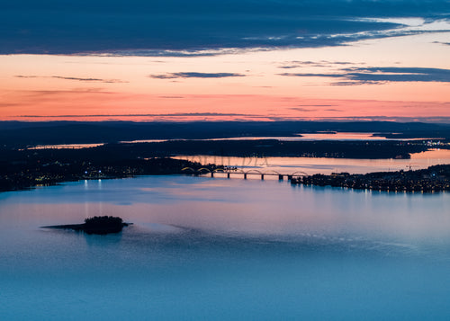 Flygfoto över Bergnäsbron och omgivande vattenlandskap i skymningen i Luleå