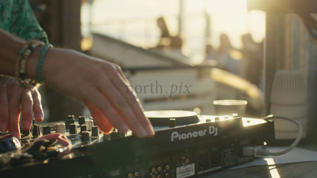 DJ Mixing Music on a Pioneer Controller at an Urban Summer Event in Lulea, Sweden During Golden Hour