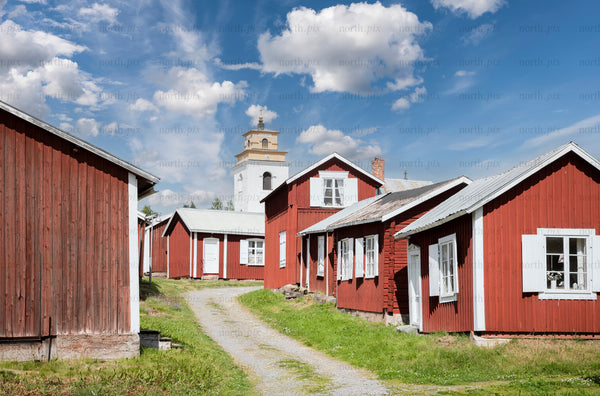 Gammelstad church town - red wooden houses and church tower along gravel path
