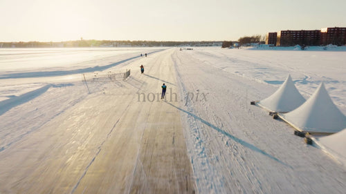 Skridskoåkare på frusen bana i Luleå, Sverige under en ljus vinterdag - Drönarfilm