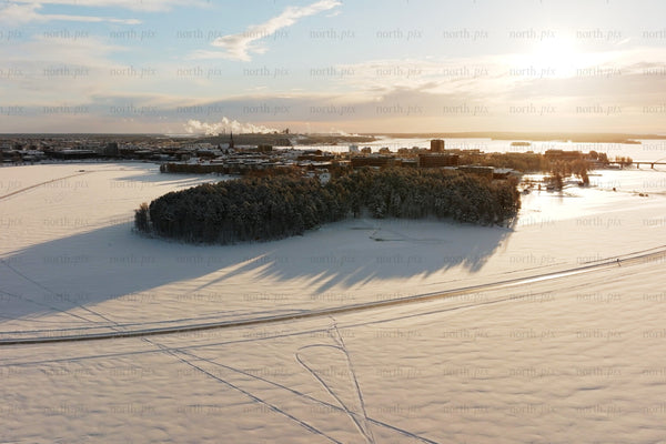 Aerial winter view over Luleå city center with snow covered island and sunset