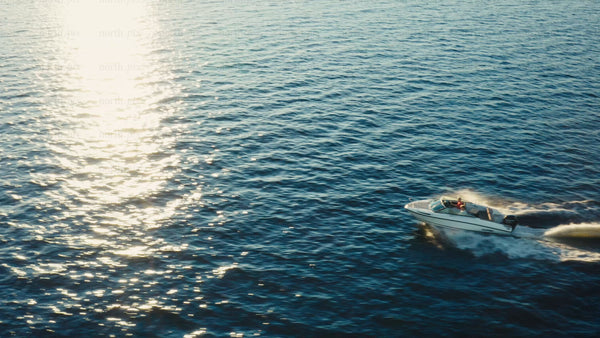Motorboat cruising through the Luleå archipelago on a sunny summer golden hour