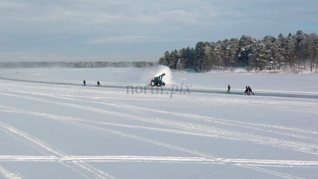 Tractor Clearing Snow on Frozen Lake in Lulea, Sweden, With People Skating and Kick Sledding