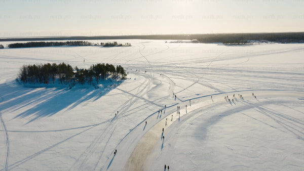 Winter wonderland in Luleå: Aerial view of people enjoying frozen lake activities on a sunny day