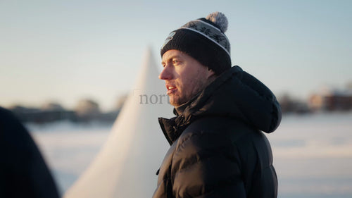 Man i vinterkläder vid en frusen sjö i Luleå, Sverige, på en solig dag