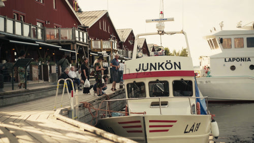 Luleå urbana sommarscen: Människor kopplar av vid de röda husen på piren under gyllene timmen