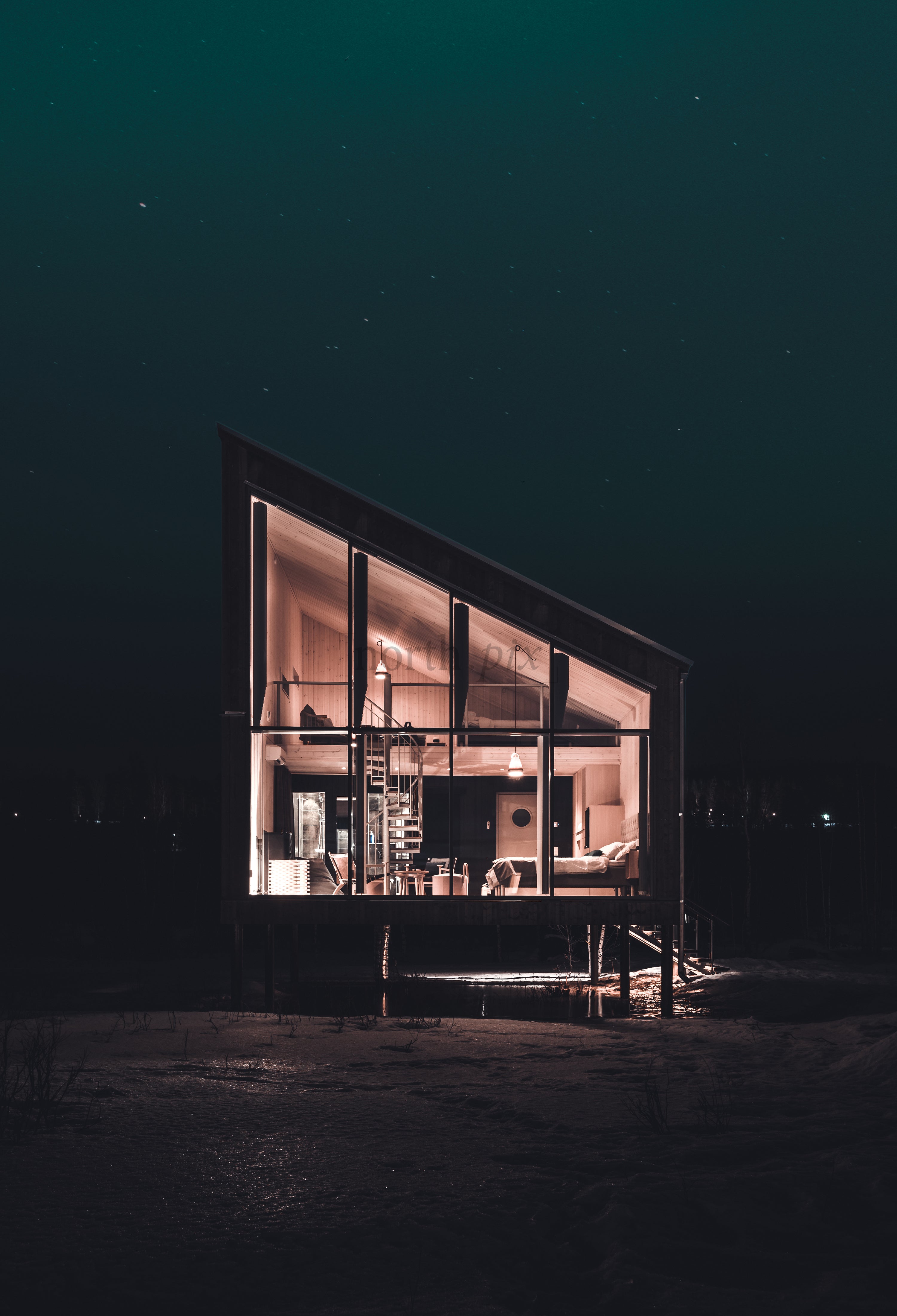 Modern glass cabin elevated on stilts at night