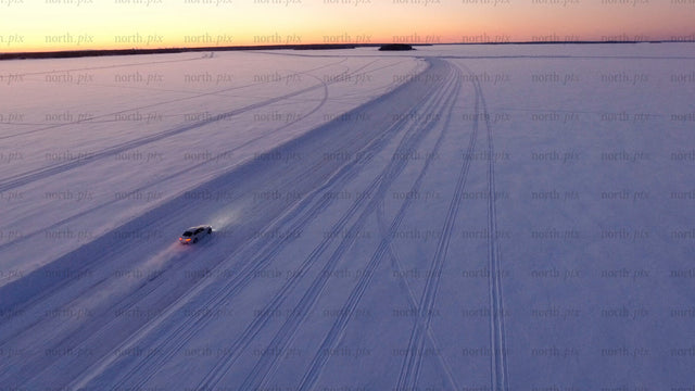 Car driving on ice road at sunset in Luleå archipelago